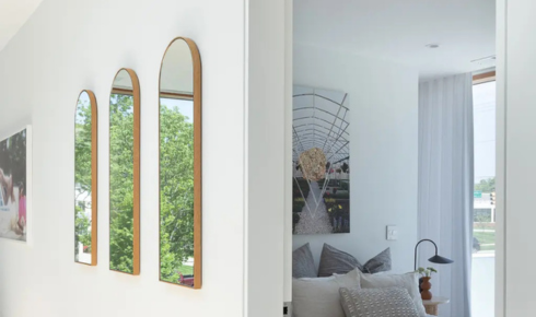In what way does placing a mirror opposite a window change how bright a living room feels?