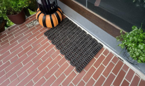 How can using entry mats inside and outside the main door keep indoor floors cleaner?