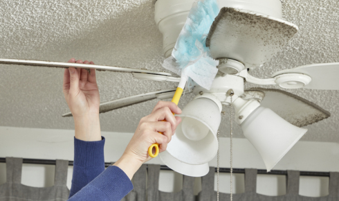 How can cleaning fan blades before summer starts make rooms feel cooler?